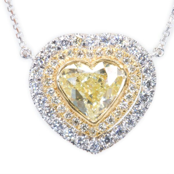 תליון יהלום לב מוקף יהלומים משני צבעי זהב - זהב לבן במסגרתו החיצונית וזהב צהוב בפנימית. הלב הפנימי הוא יהלום טבעי צהוב והאבנים הלבנות הן יהלומים לבנים. 