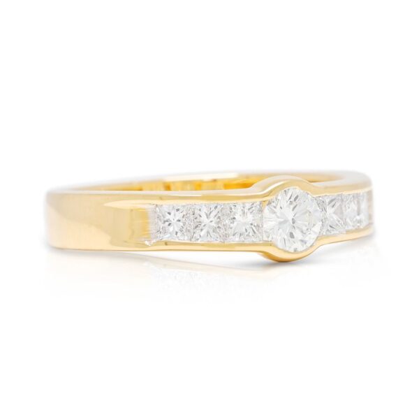 טבעת מעצימה בשיבוץ בזל עם יהלום טבעי 0.64ct בחיתוך עגול ופרינסס בזהב צהוב 18K